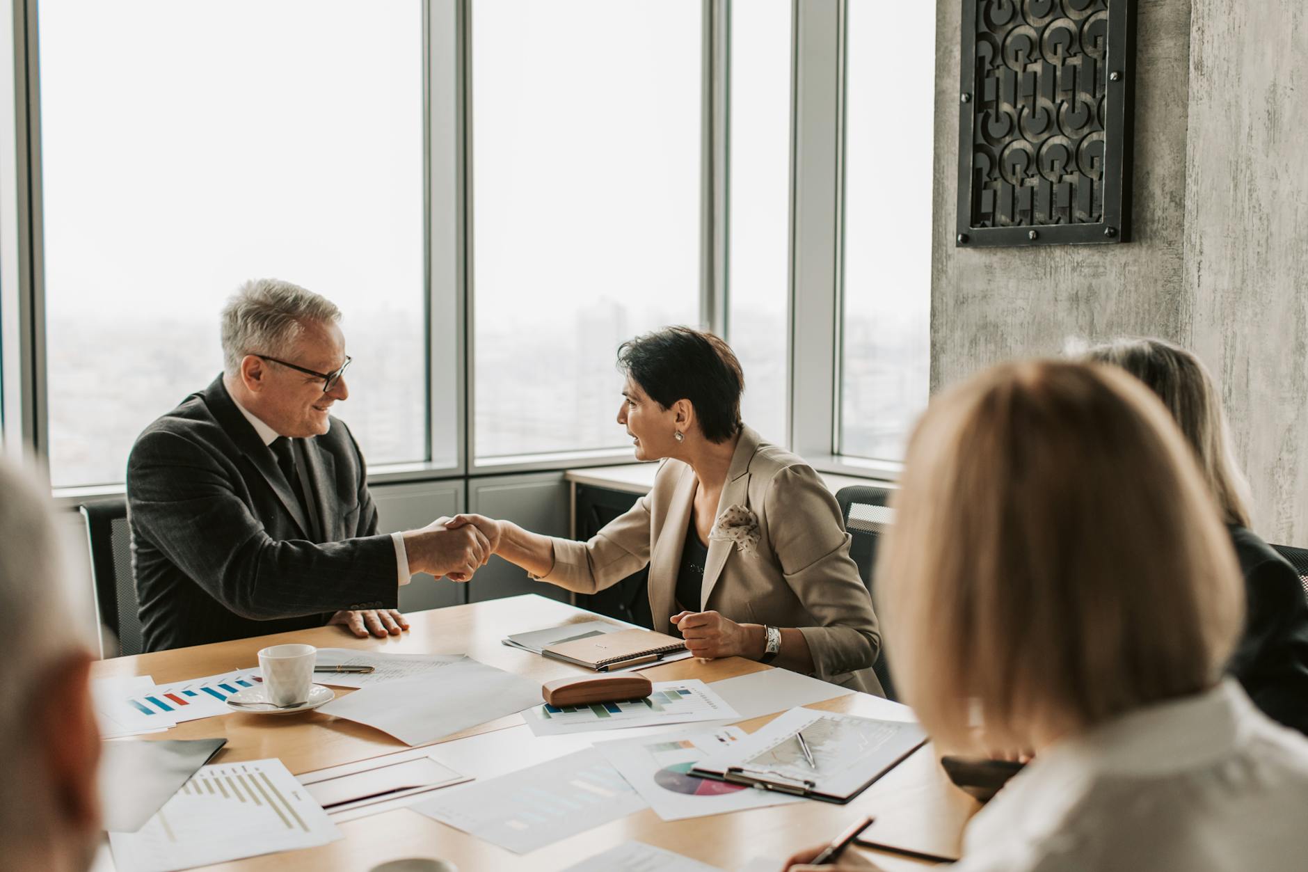 Business professionals shaking hands in meeting room after decision